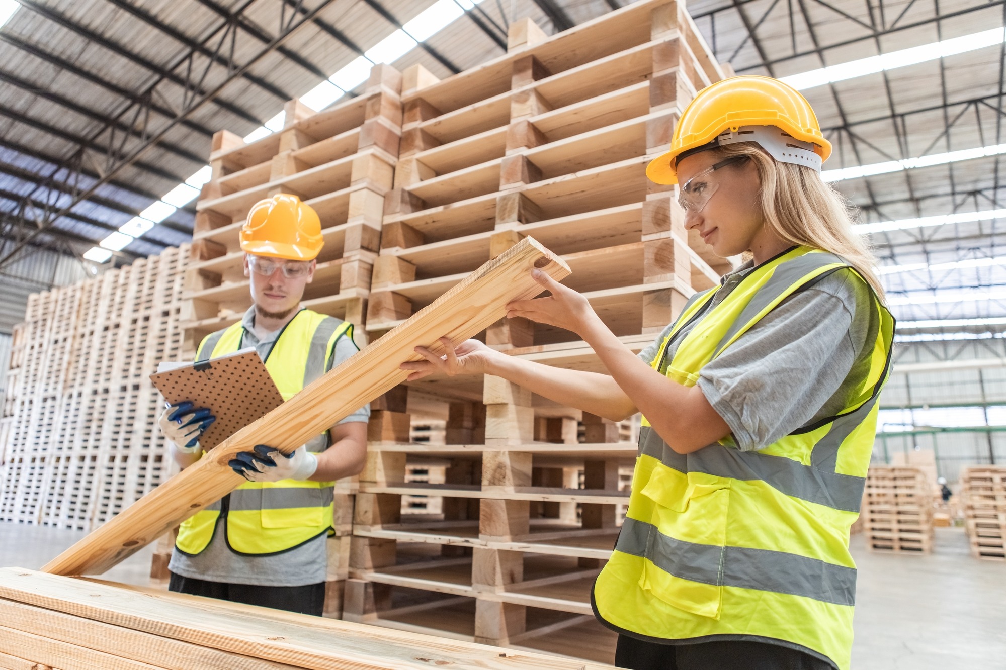 Team Engineer Carpenter Wearing Safety Uniform and Hard Hat Working Holding Clipboard Checking Quality of Wooden Products.